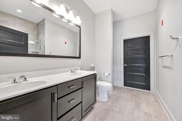 bathroom featuring baseboards, a sink, toilet, and double vanity