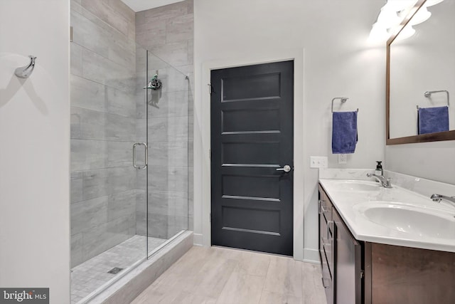 bathroom with double vanity, a stall shower, and a sink