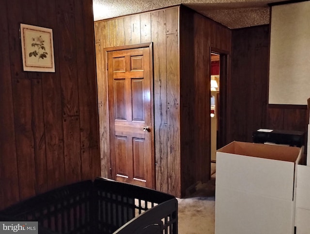 carpeted bedroom with wooden walls and a textured ceiling