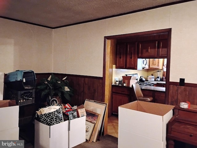 kitchen with ornamental molding, a textured ceiling, and wood walls