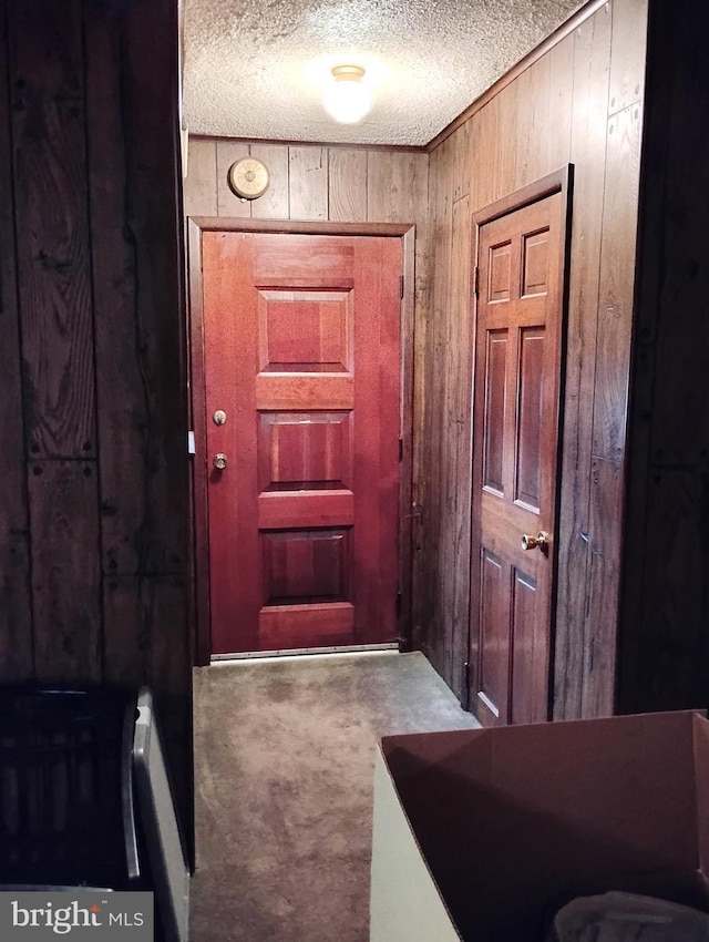 entryway featuring carpet floors, a textured ceiling, and wood walls