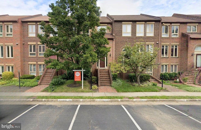 view of property with uncovered parking and stairway