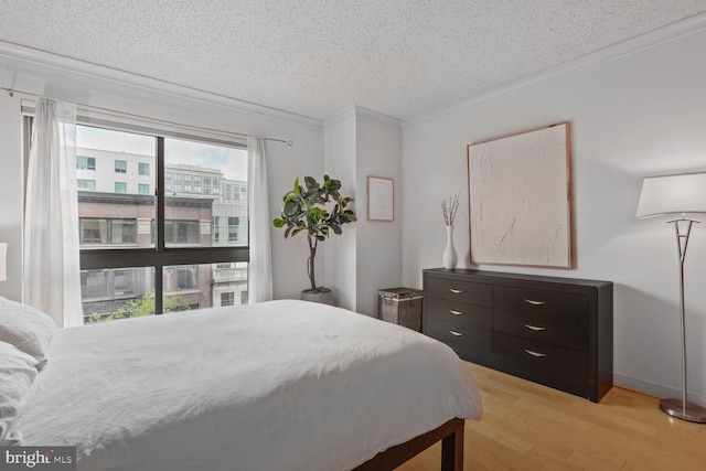 bedroom featuring a textured ceiling, light wood-style flooring, and ornamental molding