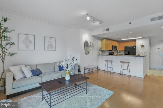 living area with light wood-type flooring, crown molding, and baseboards