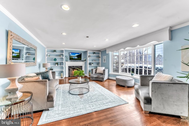 living room featuring hardwood / wood-style floors, a high end fireplace, and ornamental molding