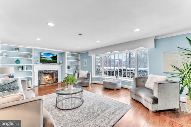 living room featuring a fireplace, crown molding, and wood-type flooring