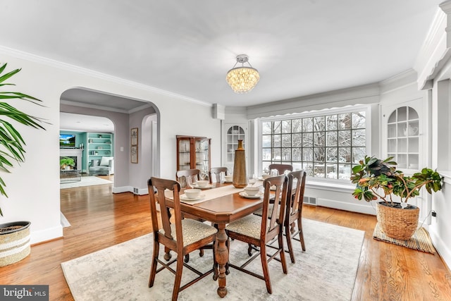 dining area featuring an inviting chandelier, ornamental molding, and light hardwood / wood-style floors