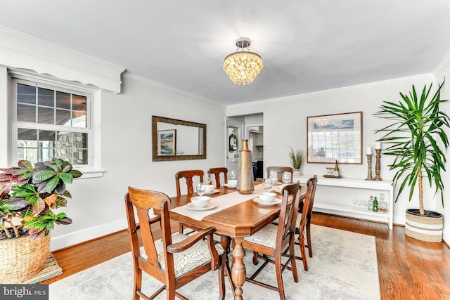 dining area with wood-type flooring, crown molding, and an inviting chandelier