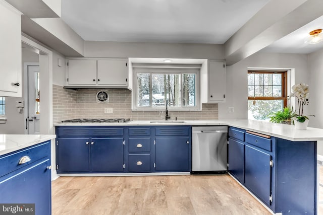 kitchen with stainless steel appliances, white cabinetry, sink, and blue cabinetry