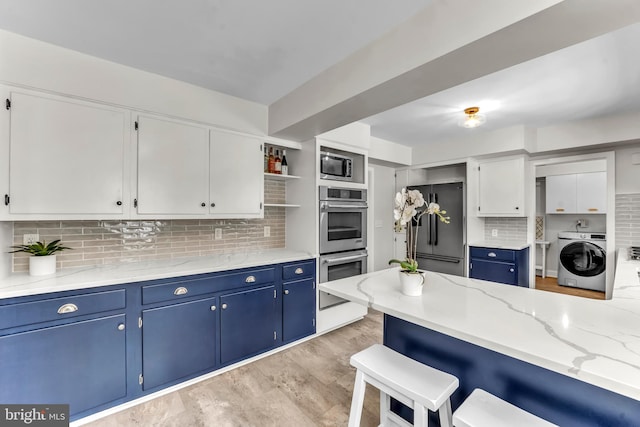 kitchen featuring blue cabinetry, appliances with stainless steel finishes, washer / clothes dryer, and white cabinets