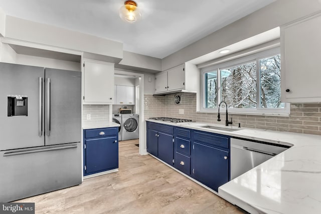 kitchen with separate washer and dryer, sink, white cabinets, stainless steel appliances, and blue cabinetry