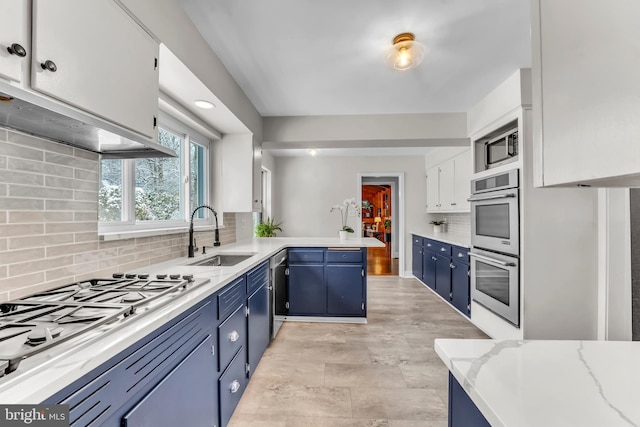 kitchen featuring blue cabinets, sink, kitchen peninsula, stainless steel appliances, and white cabinets