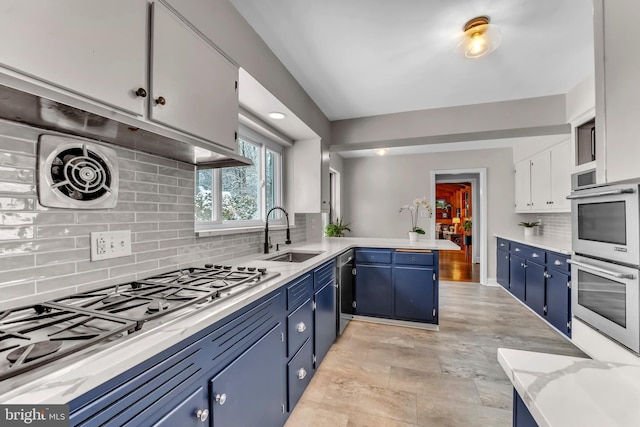 kitchen featuring sink, white cabinets, kitchen peninsula, stainless steel appliances, and blue cabinetry