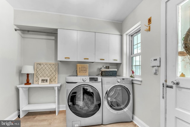 laundry area featuring cabinets, washer and clothes dryer, and light hardwood / wood-style floors