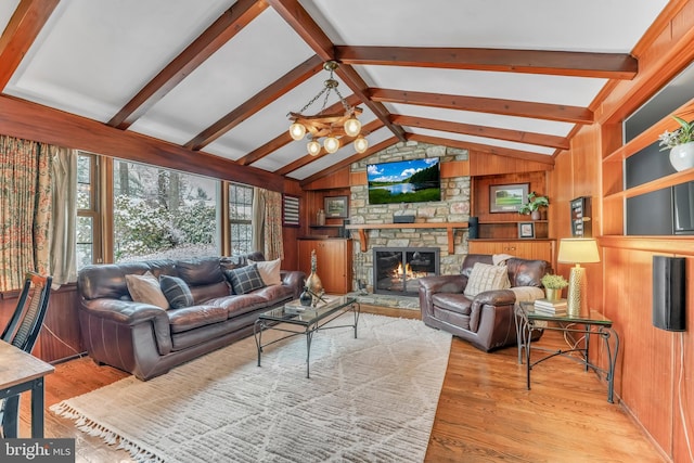 living room featuring lofted ceiling with beams, a stone fireplace, light hardwood / wood-style flooring, and wood walls