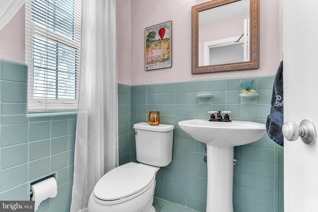 bathroom with tile walls and toilet