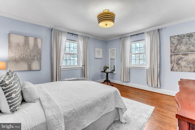 bedroom with crown molding, light hardwood / wood-style floors, and multiple windows