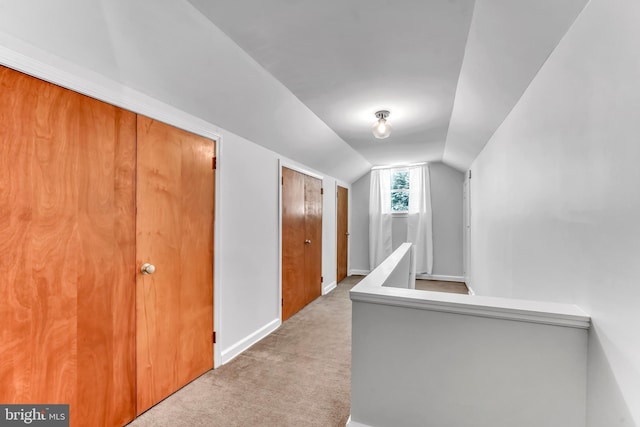 hallway featuring light carpet and lofted ceiling