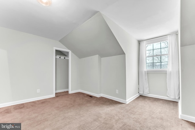 additional living space featuring light carpet and vaulted ceiling