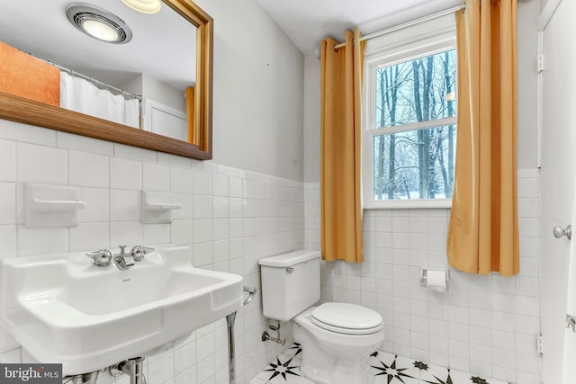 bathroom featuring sink, tile walls, and toilet