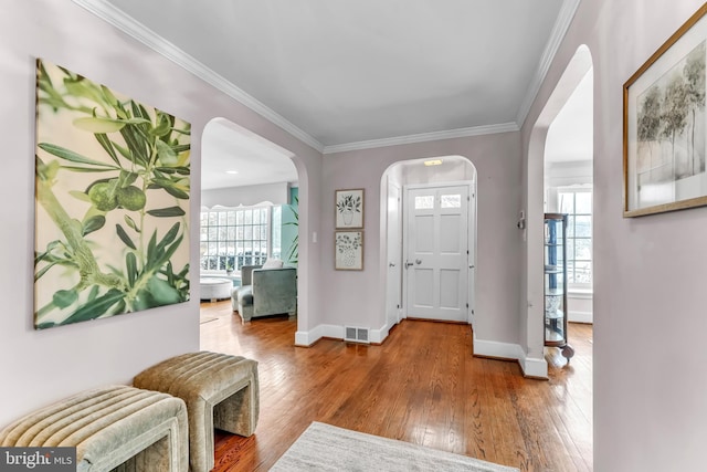 entrance foyer featuring crown molding, wood-type flooring, and plenty of natural light