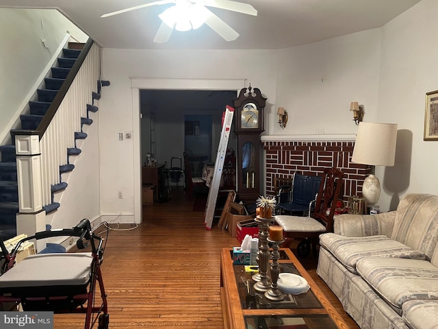 living room featuring hardwood / wood-style flooring, ceiling fan, and a brick fireplace