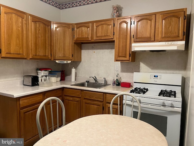 kitchen featuring tasteful backsplash, white range with gas cooktop, and sink