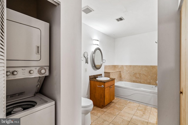 bathroom with vanity, a bath, visible vents, stacked washer / drying machine, and toilet