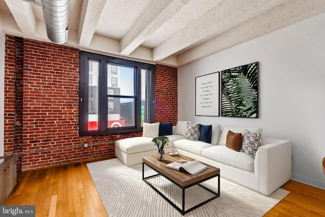 living room featuring baseboards, wood finished floors, and brick wall