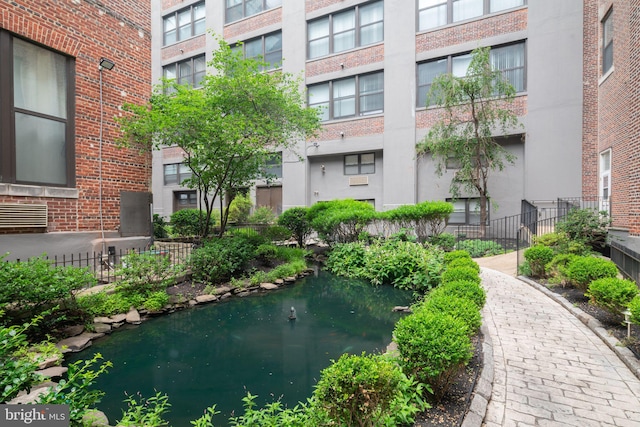 view of property's community featuring a garden pond and fence