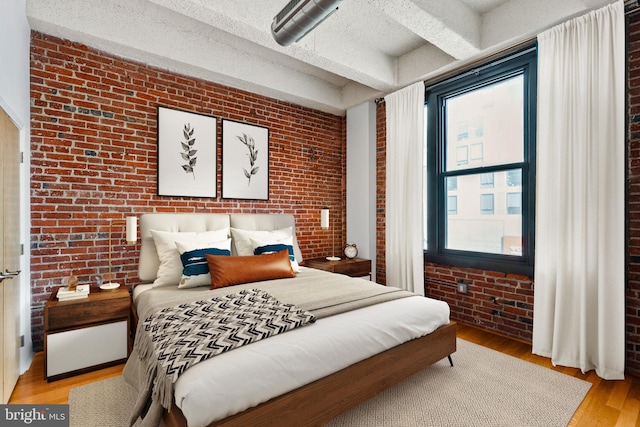 bedroom featuring wood finished floors and brick wall