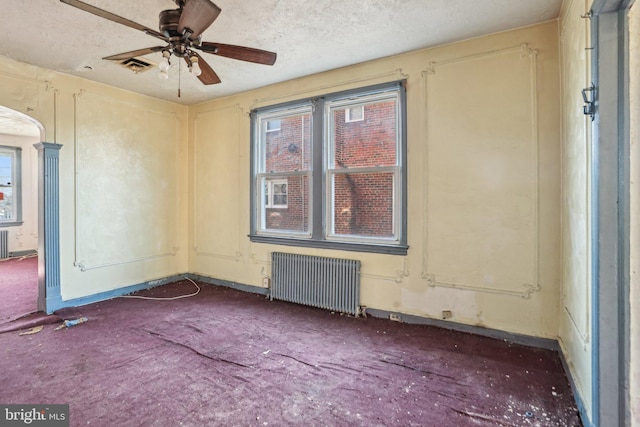 carpeted empty room with radiator, a textured ceiling, and ceiling fan