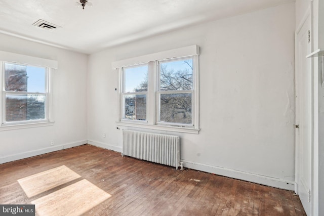 empty room with radiator and hardwood / wood-style floors