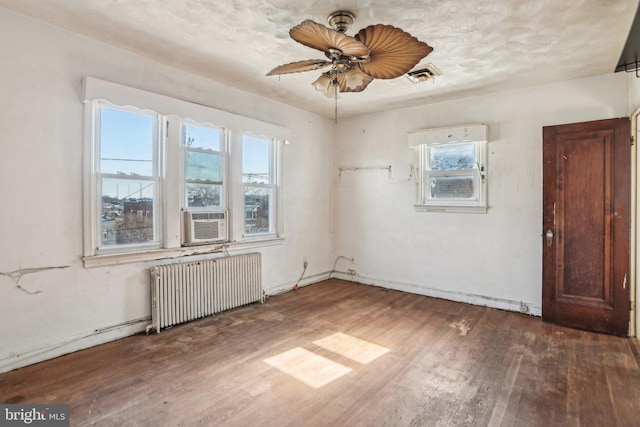 unfurnished room with radiator, dark wood-type flooring, ceiling fan, and cooling unit