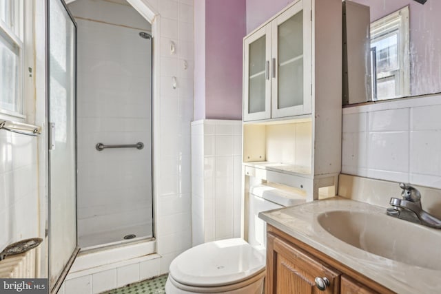 bathroom with toilet, tile walls, vanity, and walk in shower