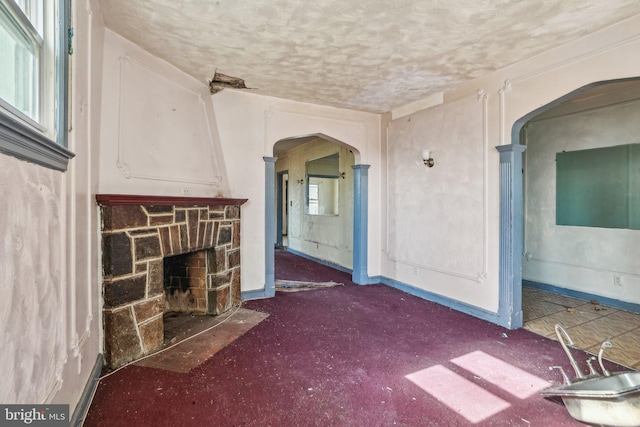 unfurnished living room with a stone fireplace and a textured ceiling