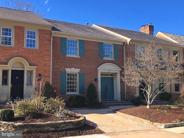 view of front of home with brick siding and a chimney