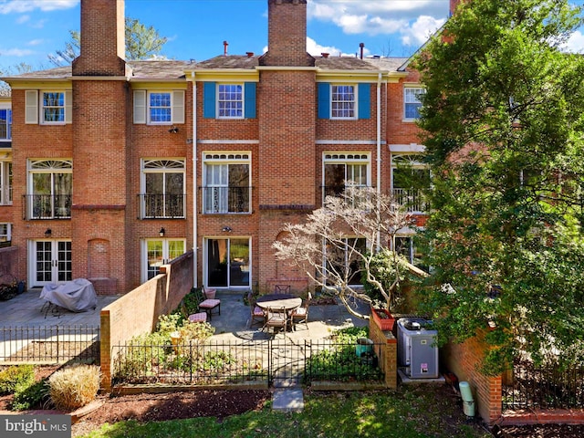 rear view of house featuring a patio area, a chimney, and brick siding