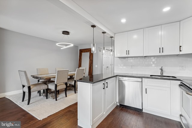 kitchen with appliances with stainless steel finishes, pendant lighting, sink, white cabinets, and dark hardwood / wood-style flooring