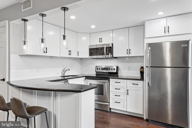 kitchen featuring appliances with stainless steel finishes, pendant lighting, white cabinets, and kitchen peninsula