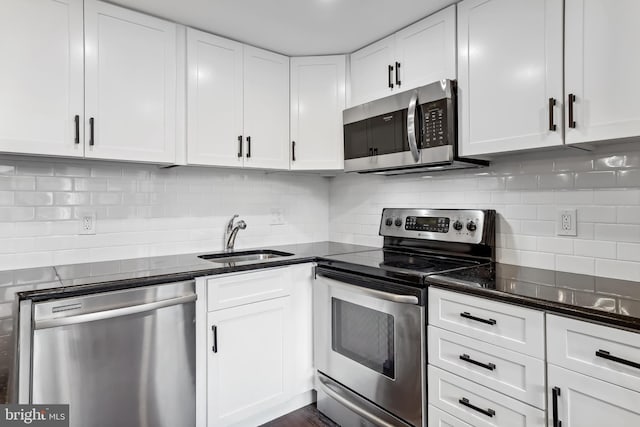 kitchen with sink, white cabinetry, stainless steel appliances, tasteful backsplash, and dark stone counters