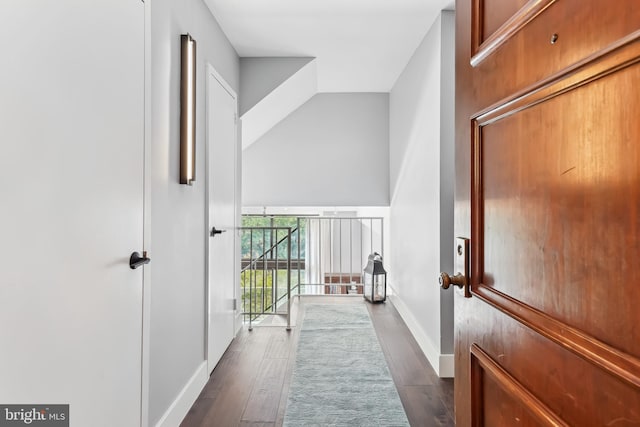 hallway with dark wood-type flooring and vaulted ceiling