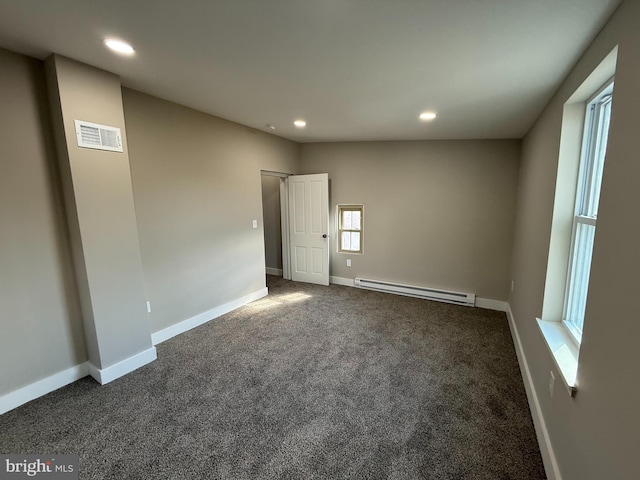 unfurnished room with dark carpet and a baseboard heating unit