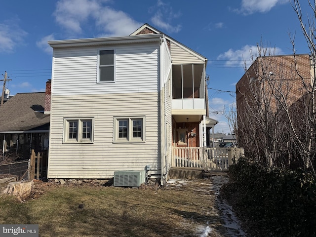 back of house featuring central AC unit and a lawn