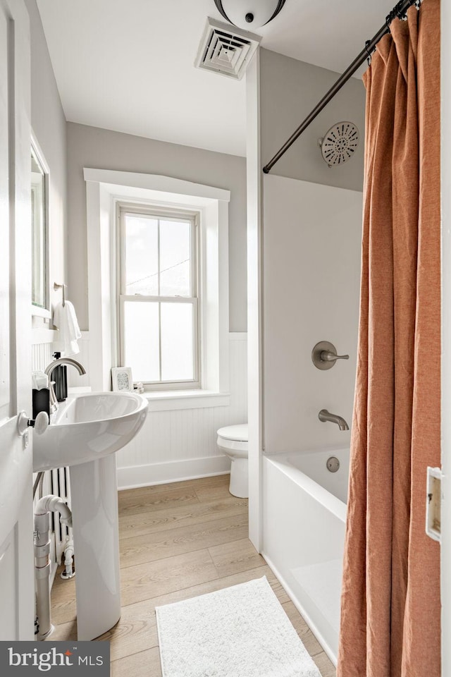 bathroom with hardwood / wood-style floors, toilet, and shower / bath combo