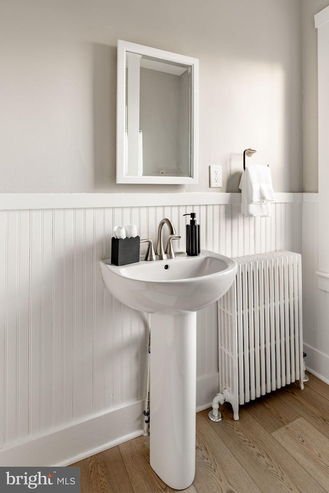 bathroom featuring sink, hardwood / wood-style flooring, and radiator heating unit