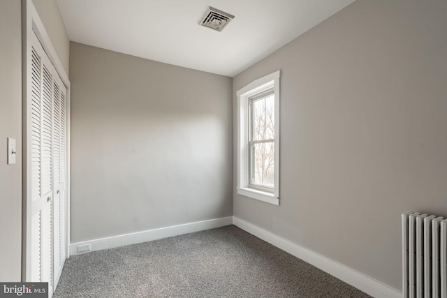 unfurnished bedroom with radiator, a closet, and carpet flooring