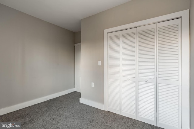 unfurnished bedroom featuring a closet and dark colored carpet