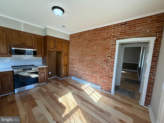 kitchen featuring light hardwood / wood-style flooring, appliances with stainless steel finishes, ornamental molding, brick wall, and backsplash