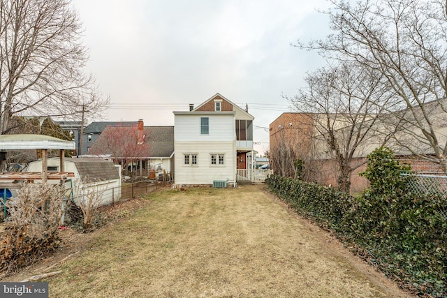 back of property with central AC unit and a yard